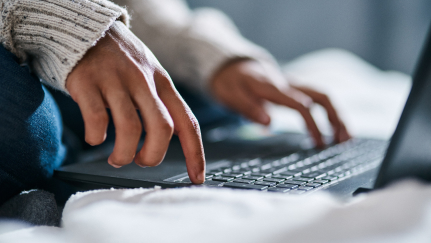 A woman’s hands on a laptop keyboard.
